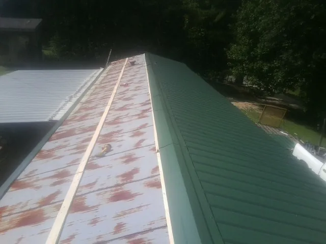 Old rusted panels beside newly installed green metal roofing — Wind Damage Roof Repair by Roofing Brothers in Richburg