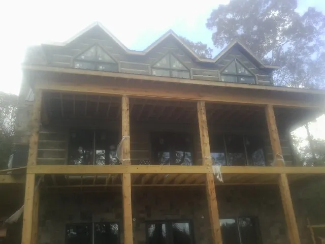Dormers and porch framing on a large log home under construction — Roof Coating work by our crew in Richburg