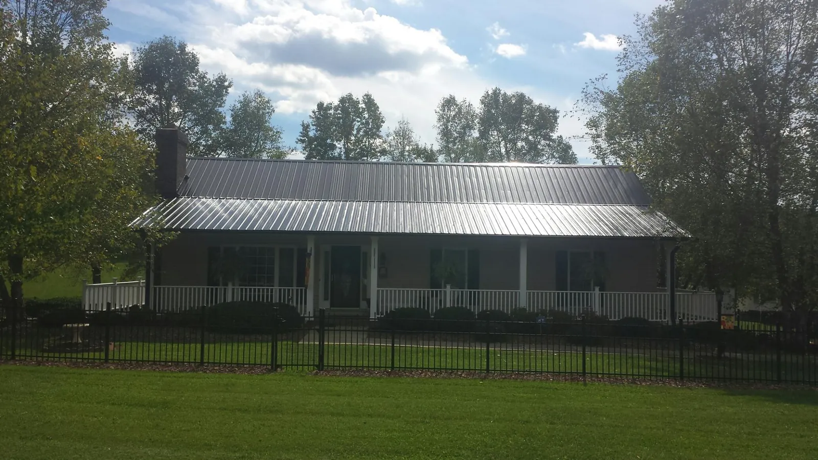 Gray metal roof on a brick ranch with a full width front porch — Gutter Guard Installation work by our crew in Richburg