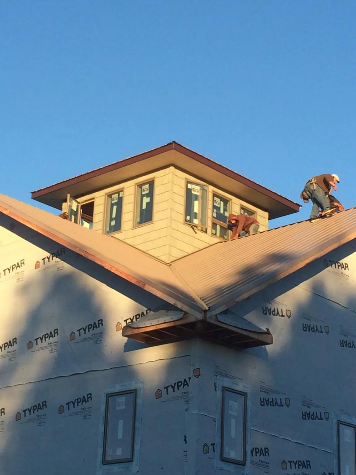 Roofers working around a rooftop cupola on a new metal roof at sunset — Roof Waterproofing in Richburg by Roofing Brothers